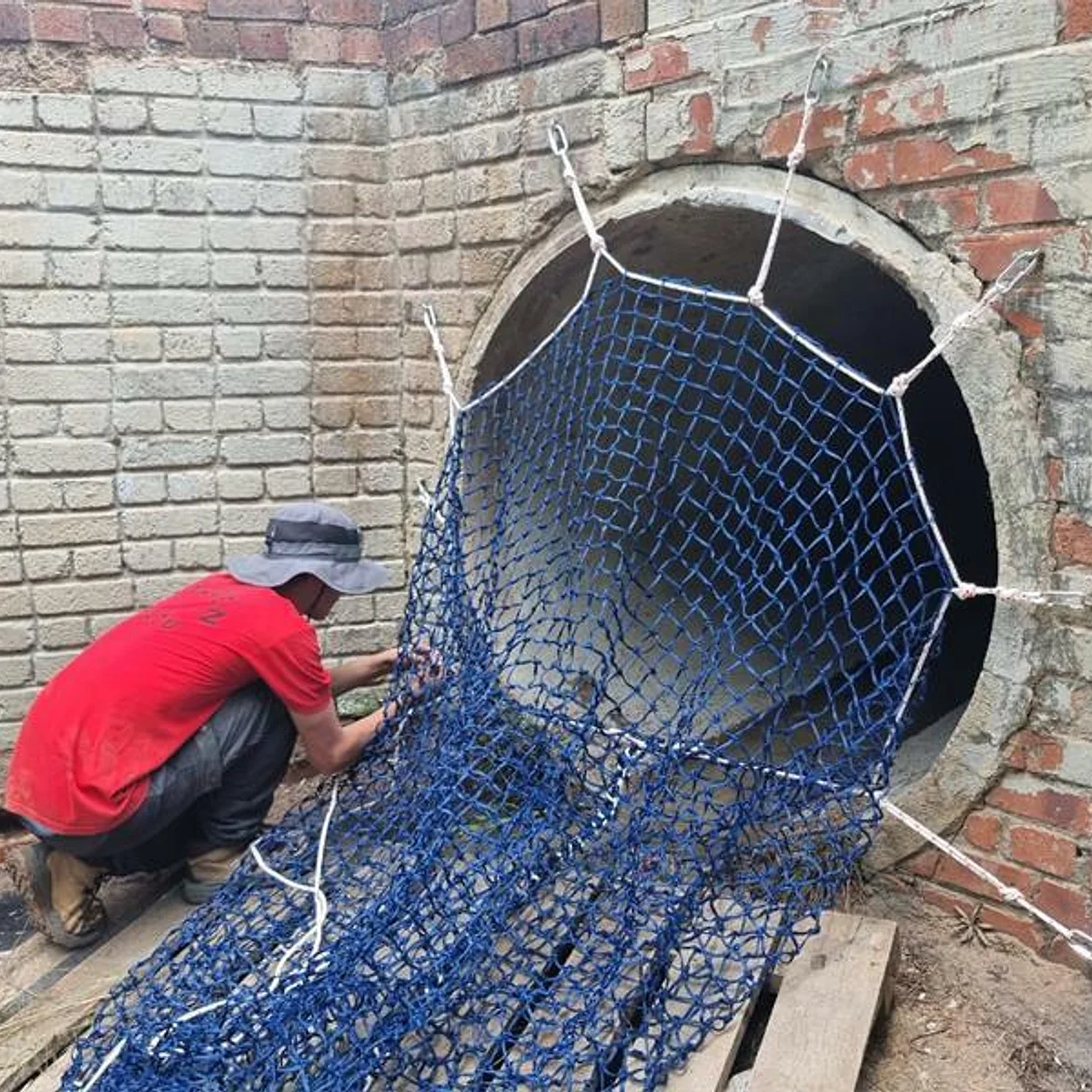 A community volunteer installing a litter catchment net at the reserve